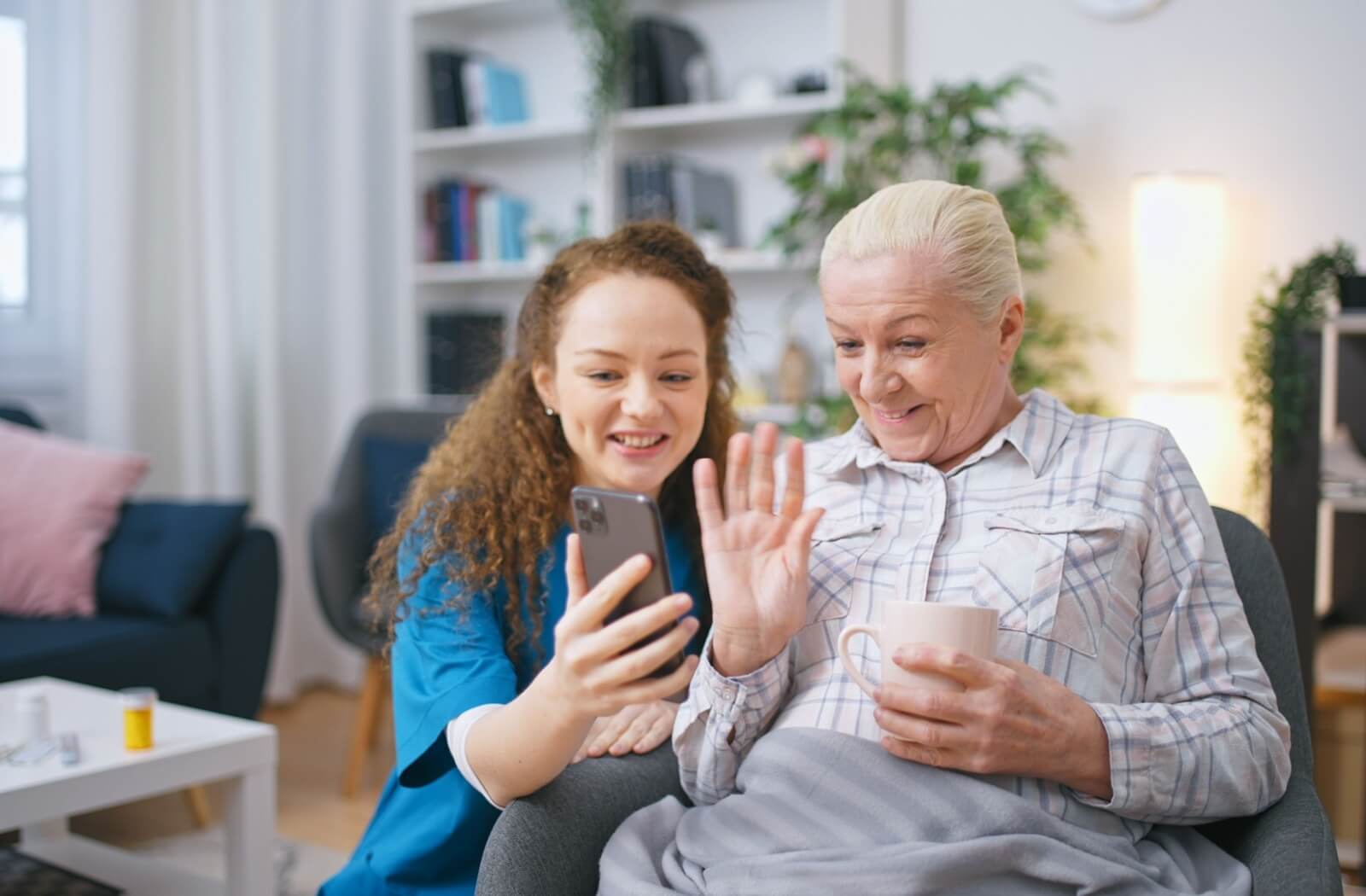 A nurse holds up a phone for a senior with dementia to virtually visit with family from their memory care home